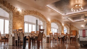 A restaurant with stone arches, wooden chairs, and tables. - Zajazd Blue (gmina Stare Miasto)