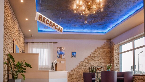 A reception area with a stone wall, a reception desk, and a seating area with chairs and a table. - Zajazd Blue (gmina Stare Miasto)