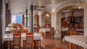 A restaurant with multiple tables and chairs, stone walls, and a view of the city. - Zajazd Blue (gmina Stare Miasto)