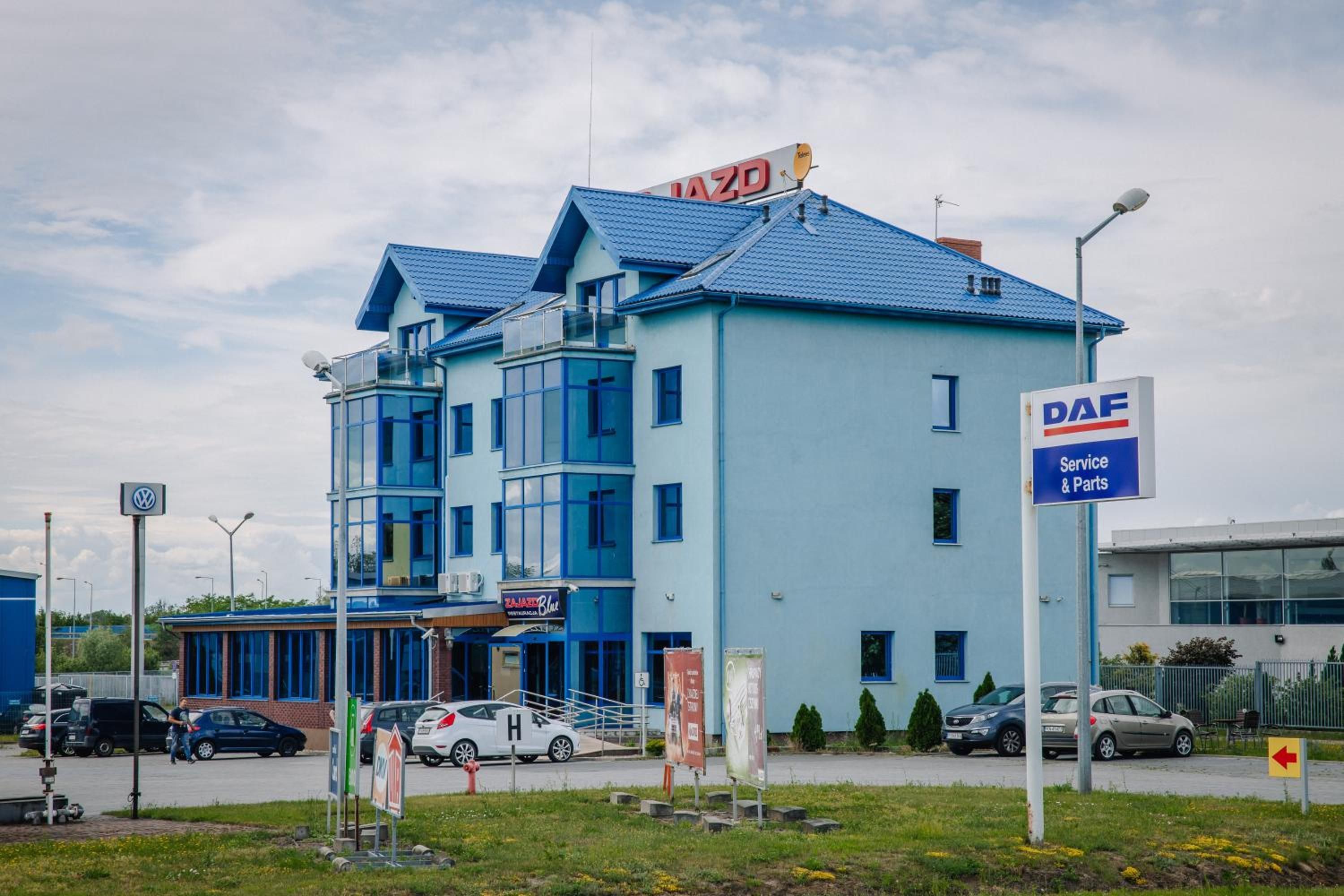 Un edificio con fachada azul, un letrero que indica DAF Service & Parts y una entrada visible.