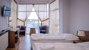 A hotel room with two beds, a desk, a chair, a TV, and a view of the outside. - Zajazd Blue (gmina Stare Miasto)