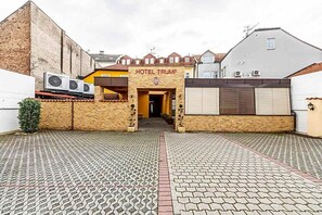 A hotel entrance with a sign reading 'HOTEL TRUMP,' a paved courtyard, and a brick building to the left. - Hotel Trumf (Mlada Boleslav)