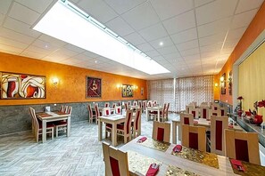 A spacious restaurant with high ceilings, multiple dining tables, and chairs. - Hotel Trumf (Mlada Boleslav)