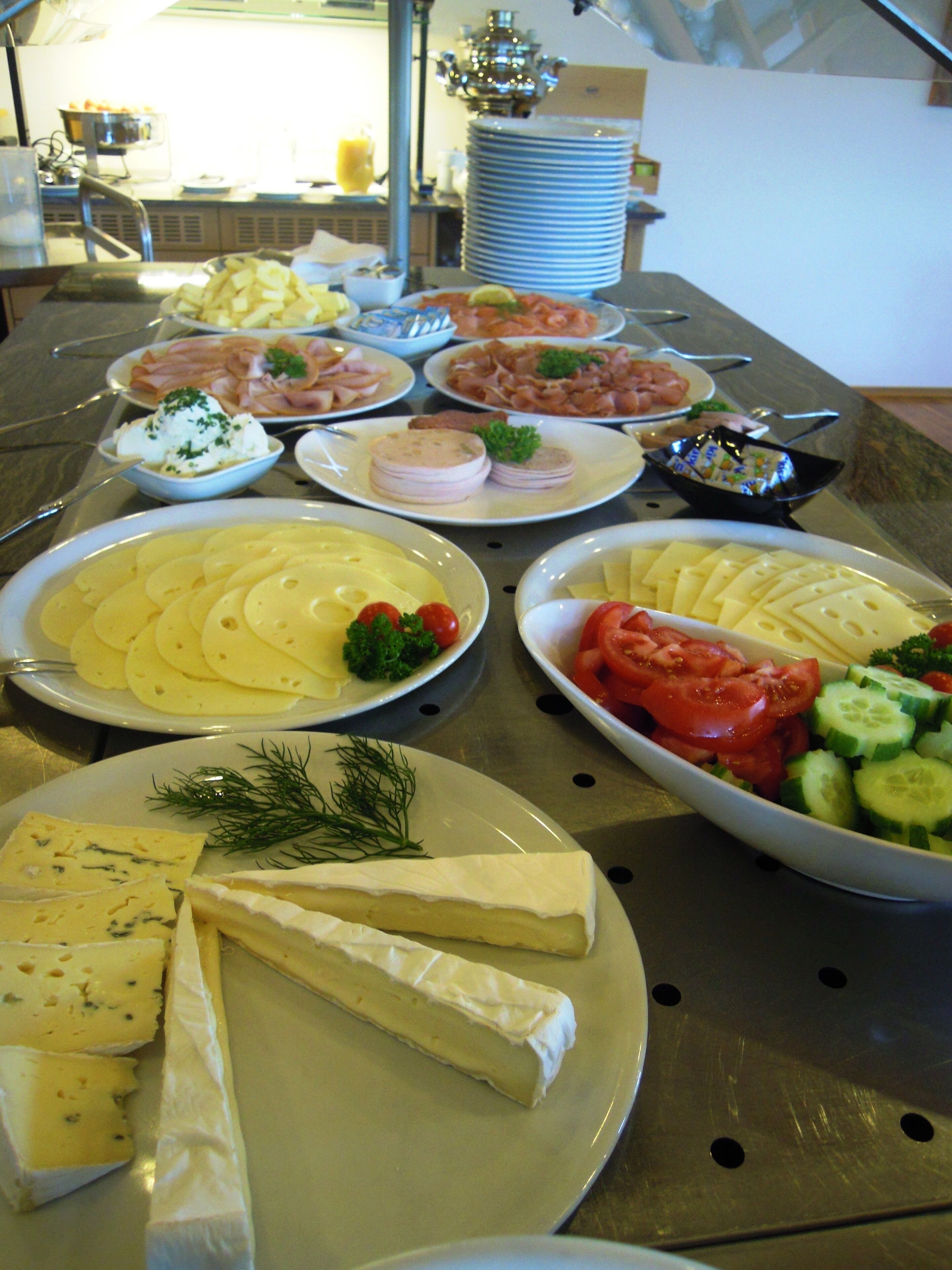 Une table de buffet proposant divers plats, notamment des fromages, des salades et des viandes.