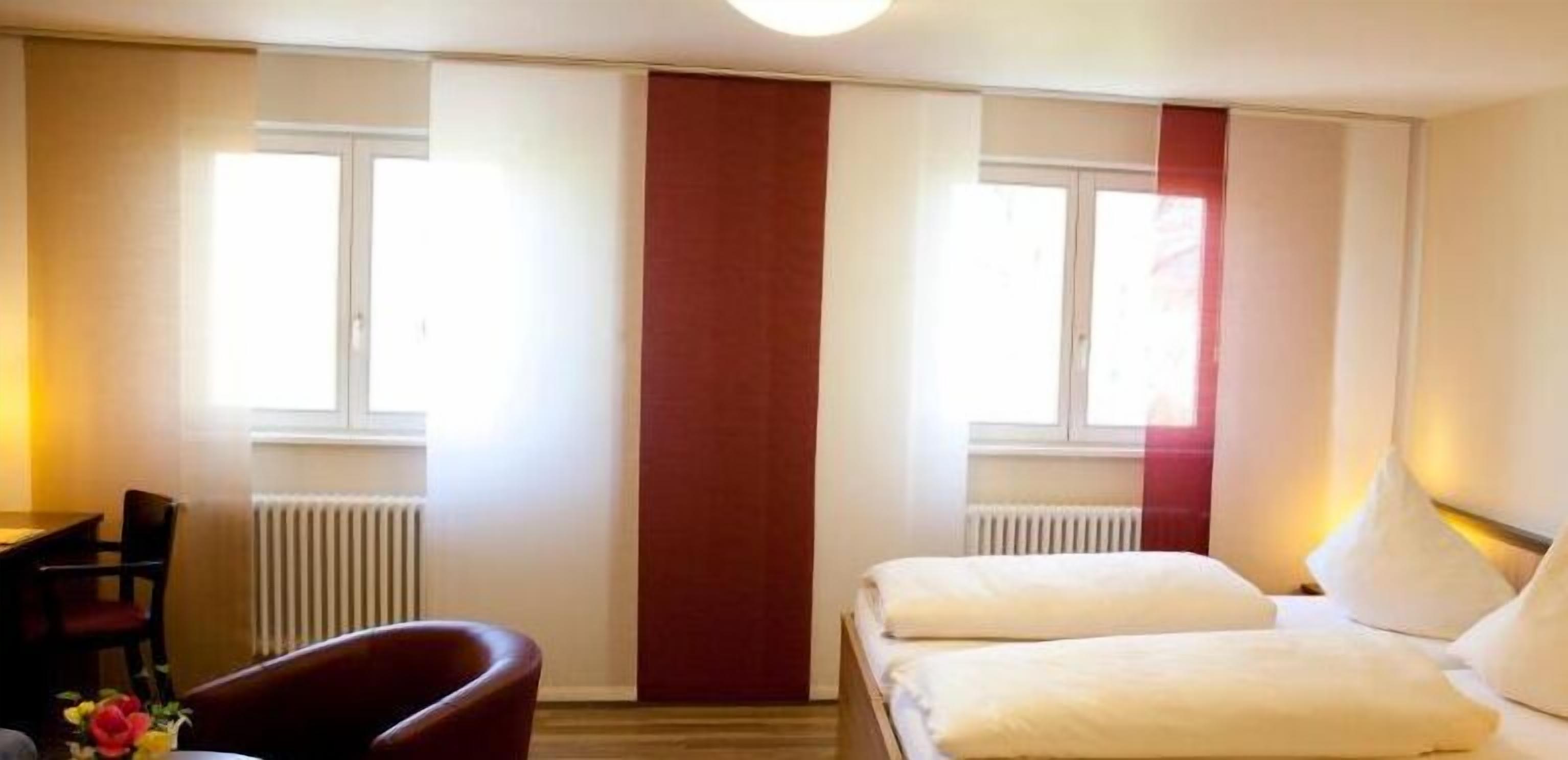 Une chambre d’hôtel avec deux lits, un bureau et une chaise.