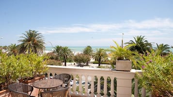 Un balcone con sedie in vimini e vista sul mare.