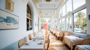 Un ristorante con un'ampia sala da pranzo, tovaglie bianche e sedie in vimini.
