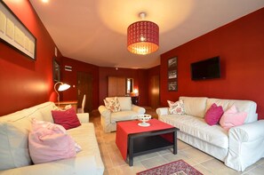 Una sala de estar con paredes rojas, sofás blancos y una araña.