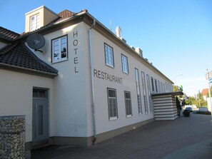 A building with 'HOTEL RESTAURANT' signage, a satellite dish, and a garage door.