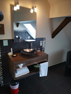 Une salle de bain moderne avec un meuble-lavabo en bois, un grand miroir et un pare-chocs en carreaux noirs et blancs.