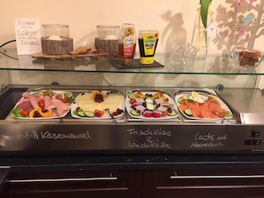 A buffet with various food options including meats, cheeses, and fruits.