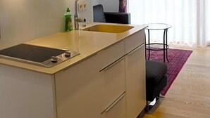 A modern kitchen with a built-in island, a sink, and overhead lighting. - Landhotel Grv Nenbach (Bad Groenenbach)