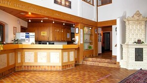 Una zona de recepción con mostrador de madera, chimenea y piso de baldosas.