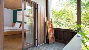A room with a bed, a wooden ladder, and a view of greenery outside. - Landhotel Grv Nenbach (Bad Groenenbach)