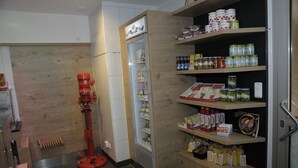 Une cuisine équipée d’un réfrigérateur, d’étagères remplies de produits alimentaires et d’un appareil électroménager rouge.