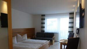 Une chambre d’hôtel avec deux lits, un canapé, une chaise, une table et un téléviseur.