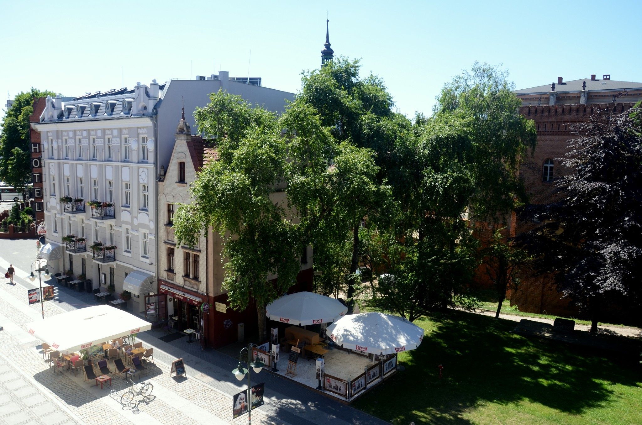 Ein Hotel mit Außenbereich, einem Kirchturm und einem Backsteinhaus.