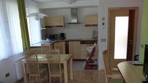 A compact living space with a dining area, kitchenette, and a TV. - Apartments Veno (Lasko)