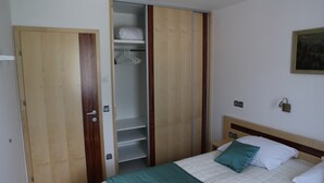 A bedroom with a bed, a closet, and a painting on the wall. - Apartments Veno (Lasko)