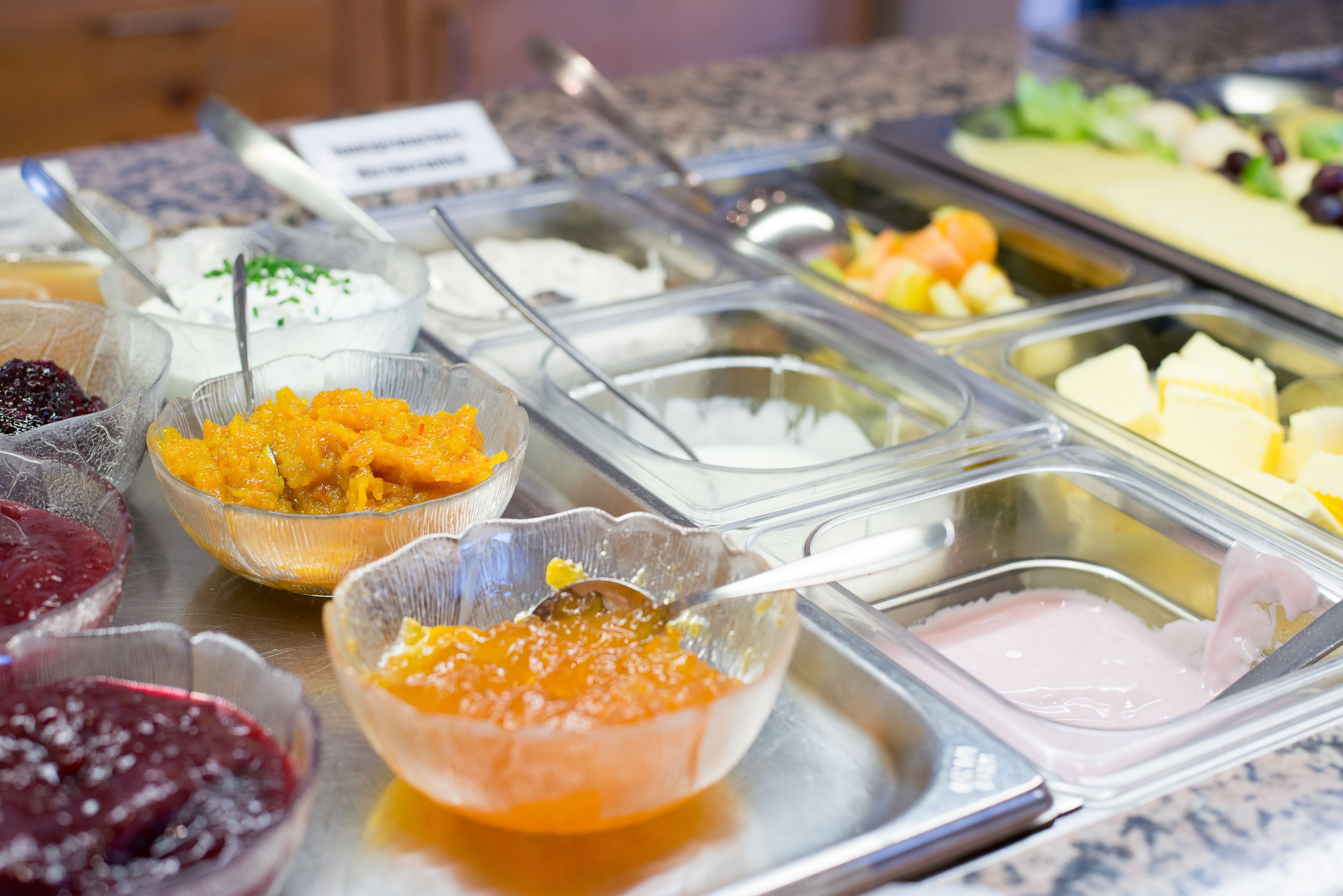 Un bufé con diversas opciones de comida, incluyendo frutas, quesos y patés.