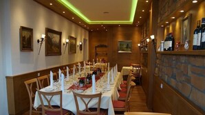 A long dining table set for a meal in a warmly lit room with wooden walls and stone accents. - Wellness Privathotel Post AN DER Therme (Badenweiler)