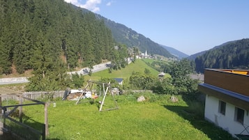 A rural landscape with a grassy area, a wooden fence, and a building with a sloped roof.