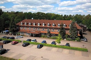 A large building with multiple windows and a parking lot with several cars.