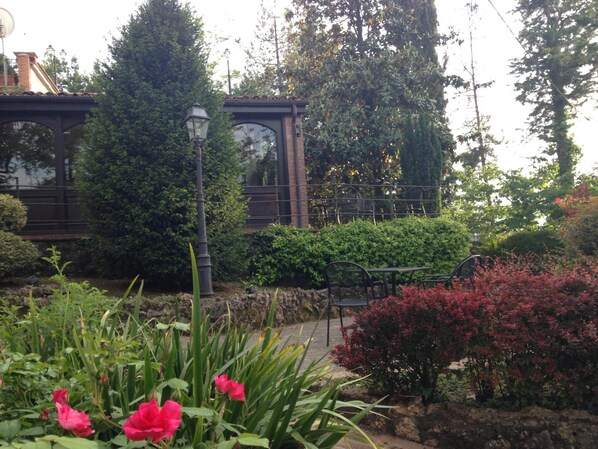 A garden with a bridge, a lamp post, and a table with chairs.