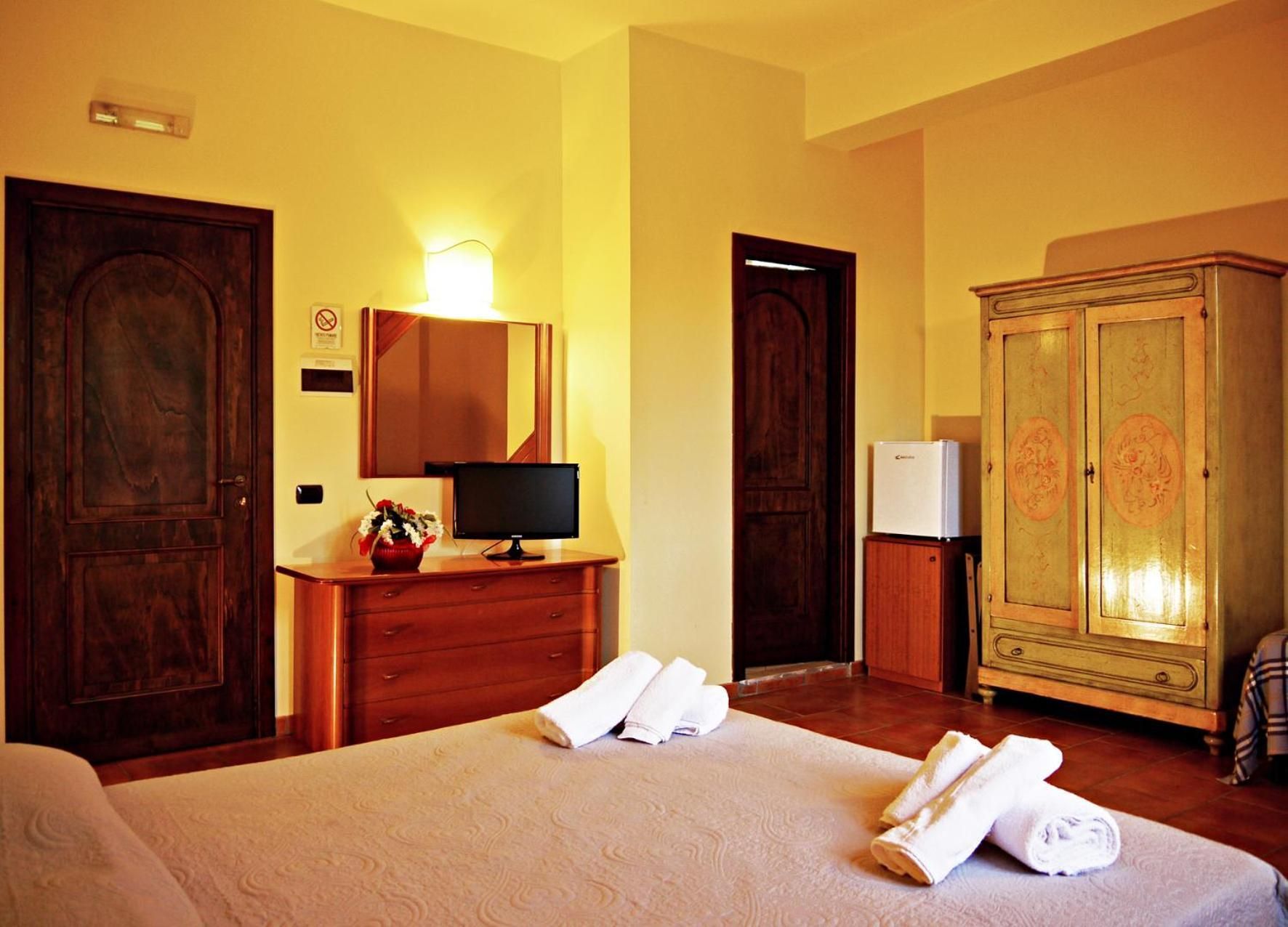 Una habitación de hotel con una cama, un escritorio con una computadora, un armario y una puerta.
