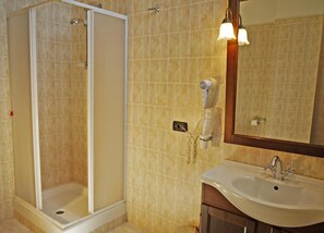 A bathroom with a shower, a sink, and a mirror.