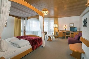 A hotel room with a bed, a desk, a television, and a sofa.