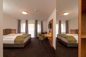A hotel room with two beds, a desk, a chair, and a TV.
