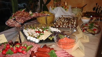 Una mesa de buffet con diversos alimentos, incluyendo carnes, quesos y verduras.