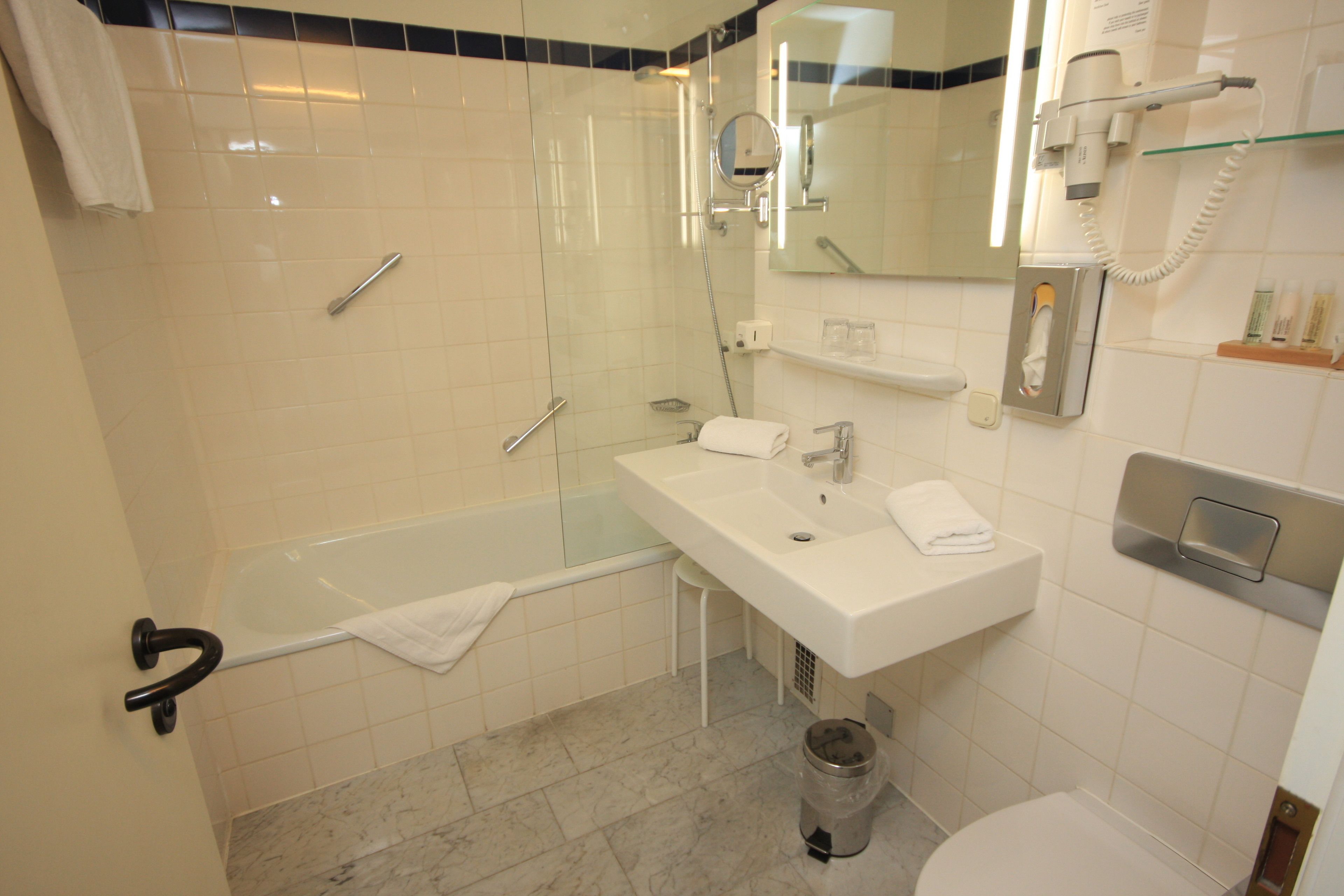 A bathroom with a glass-enclosed shower, a white sink, a mirror, and a toilet.
