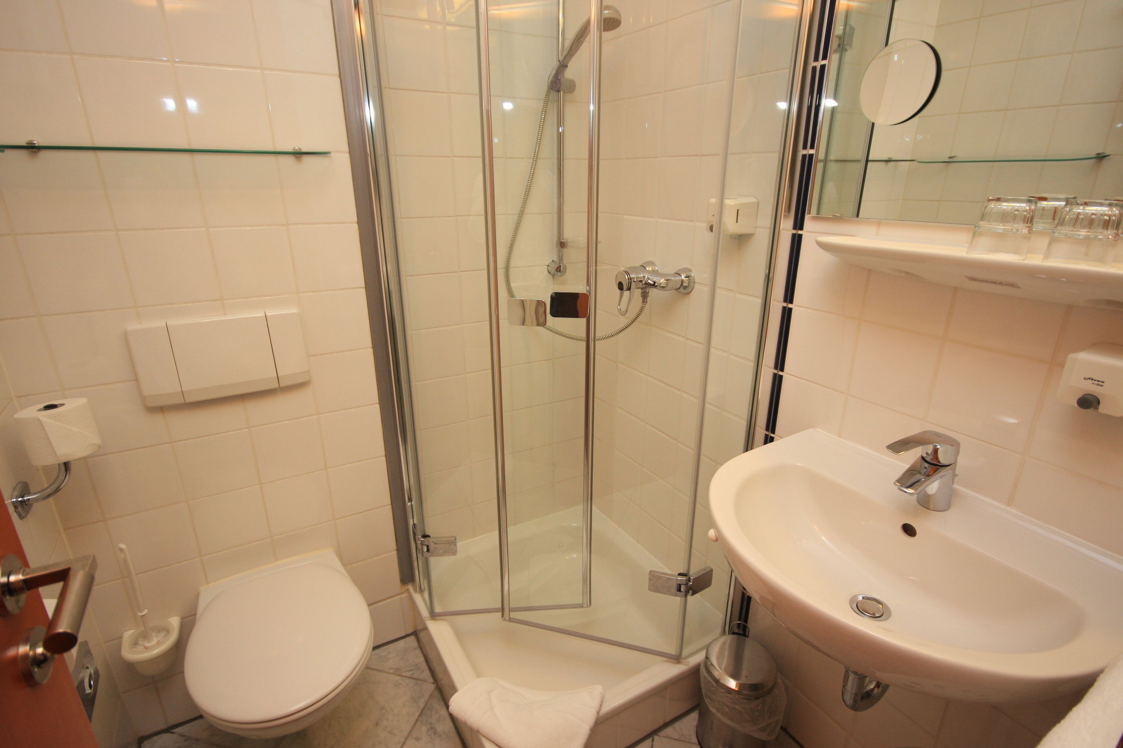 A bathroom with a glass-enclosed shower, a white sink, and a toilet.