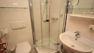 A bathroom with a glass-enclosed shower, a white sink, and a toilet.