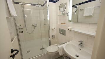 A bathroom with a glass-enclosed shower, a toilet, a sink, and a mirror.