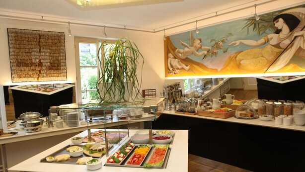 Un espace buffet proposant divers plats, une grande peinture et une plante décorative.