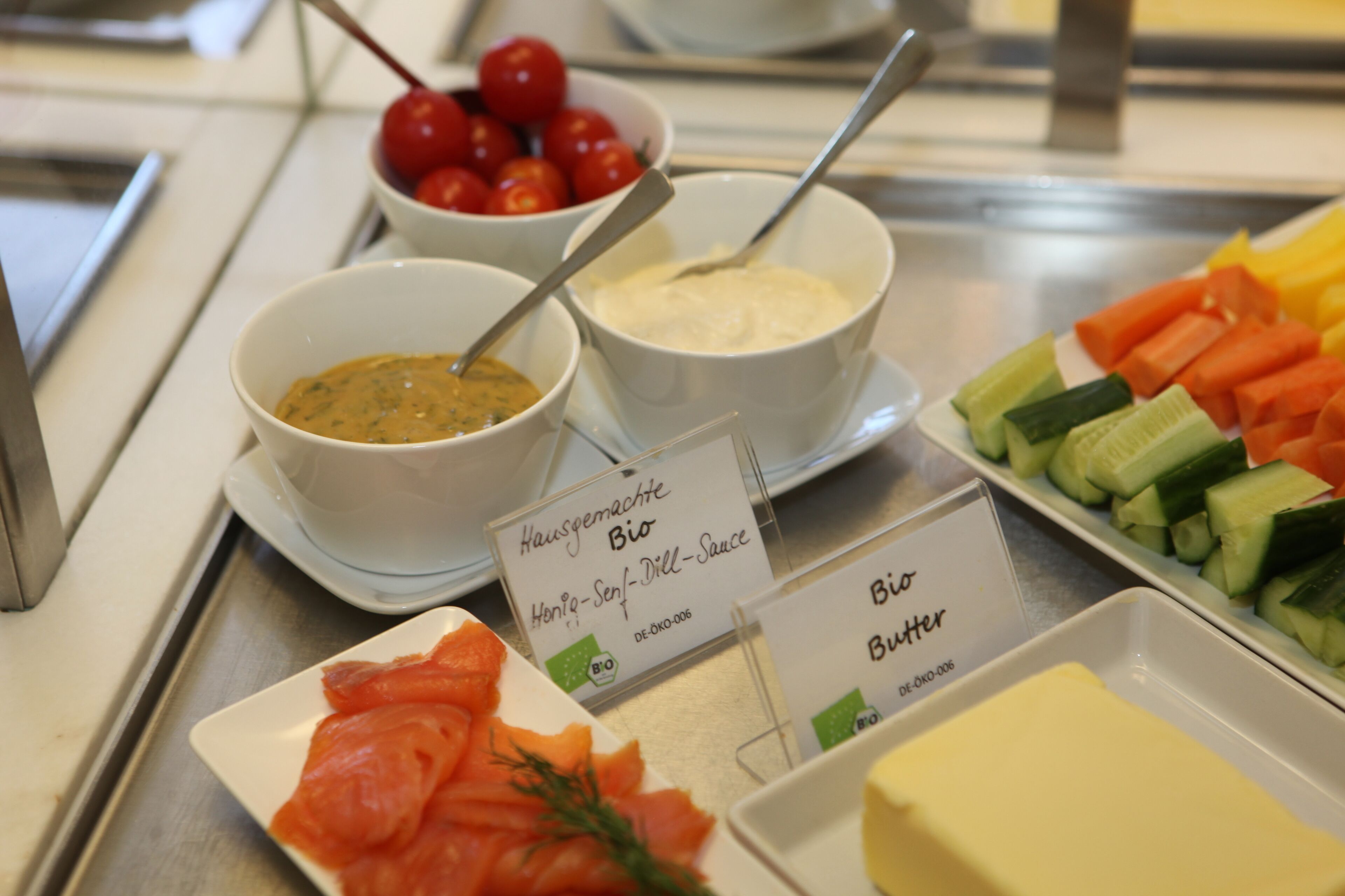 A buffet with various food options including smoked salmon, butter, and fresh vegetables.