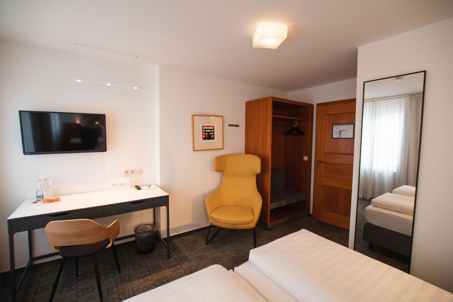 Une chambre d’hôtel comprenant un lit, un bureau avec une chaise, une télévision, une armoire et un miroir.