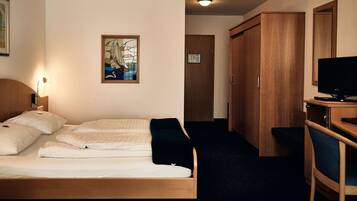 Una camera d'albergo con un letto, una scrivania con un computer, una televisione e un armadio.