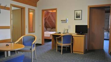 Habitació d'hotel amb llit, escriptori, ordinador, televisió, cadira i taula petita.