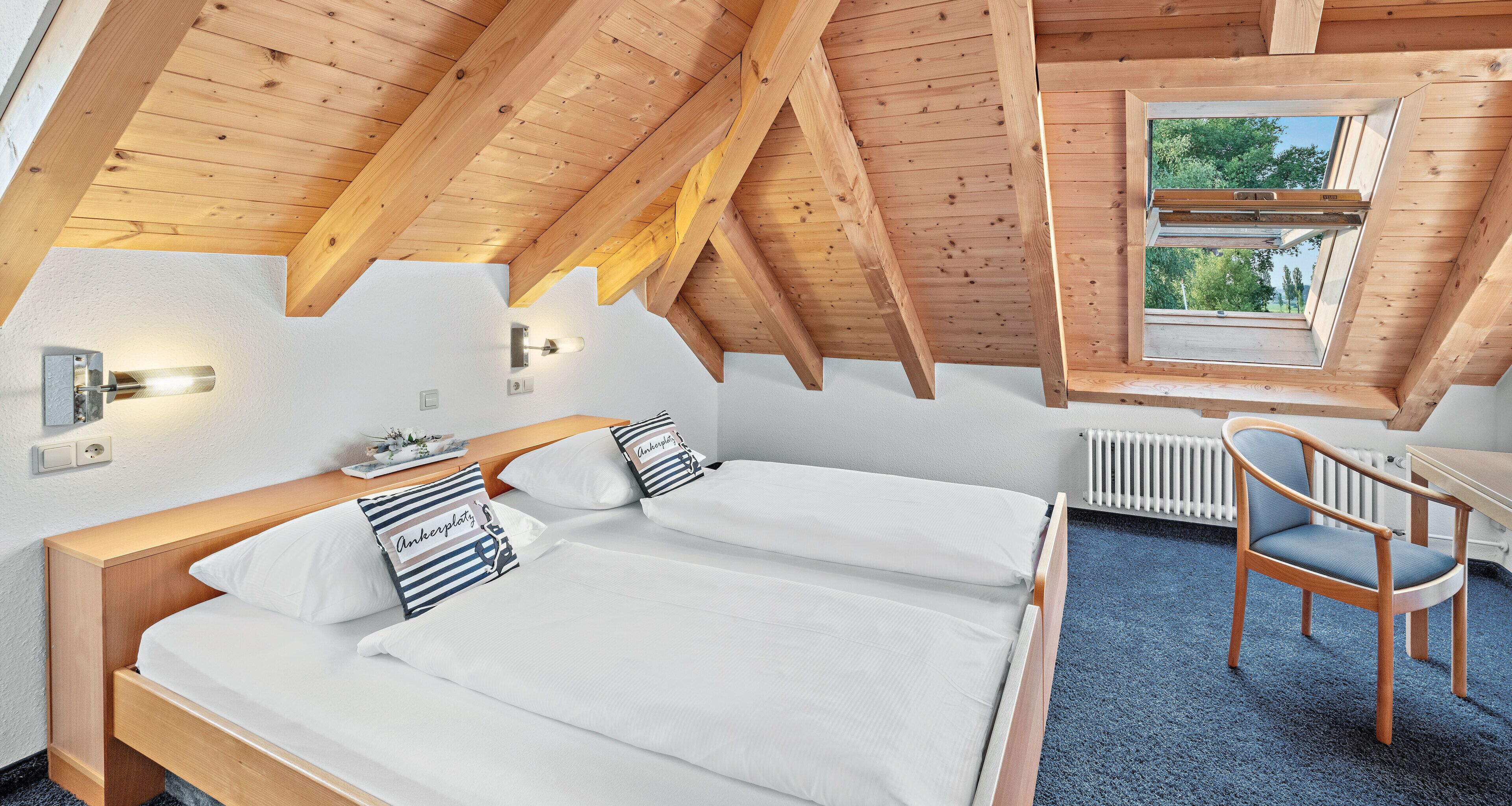 Une chambre avec deux lits, une fenêtre, une chaise et un radiateur.