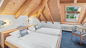 Une chambre avec deux lits, une fenêtre, une chaise et un radiateur.