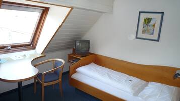 Ein kleiner, kompakter Raum mit Bett, Schreibtisch, Stuhl, Fernseher und Telefon.