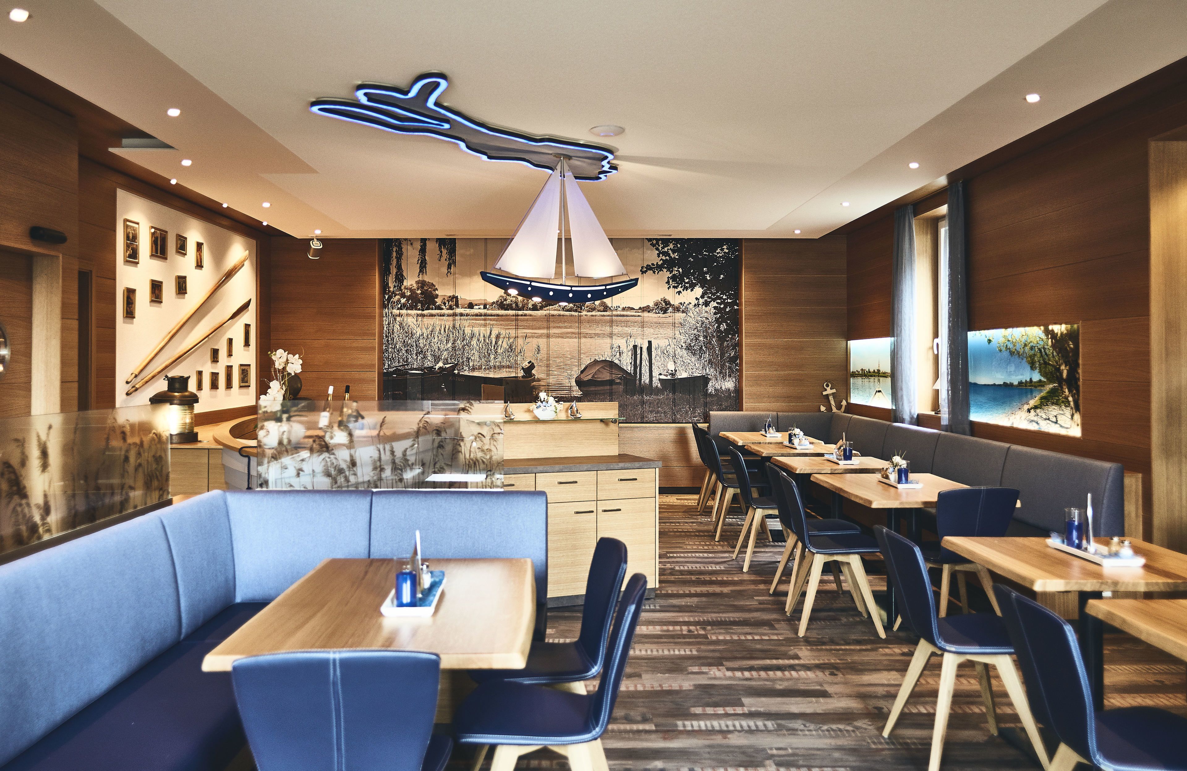 A modern restaurant with wooden walls, blue seating, and a central island.