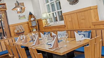 Una mesa de comedor de madera con sillas tapizadas en azul, dispuesta con copas de vino y servilletas.