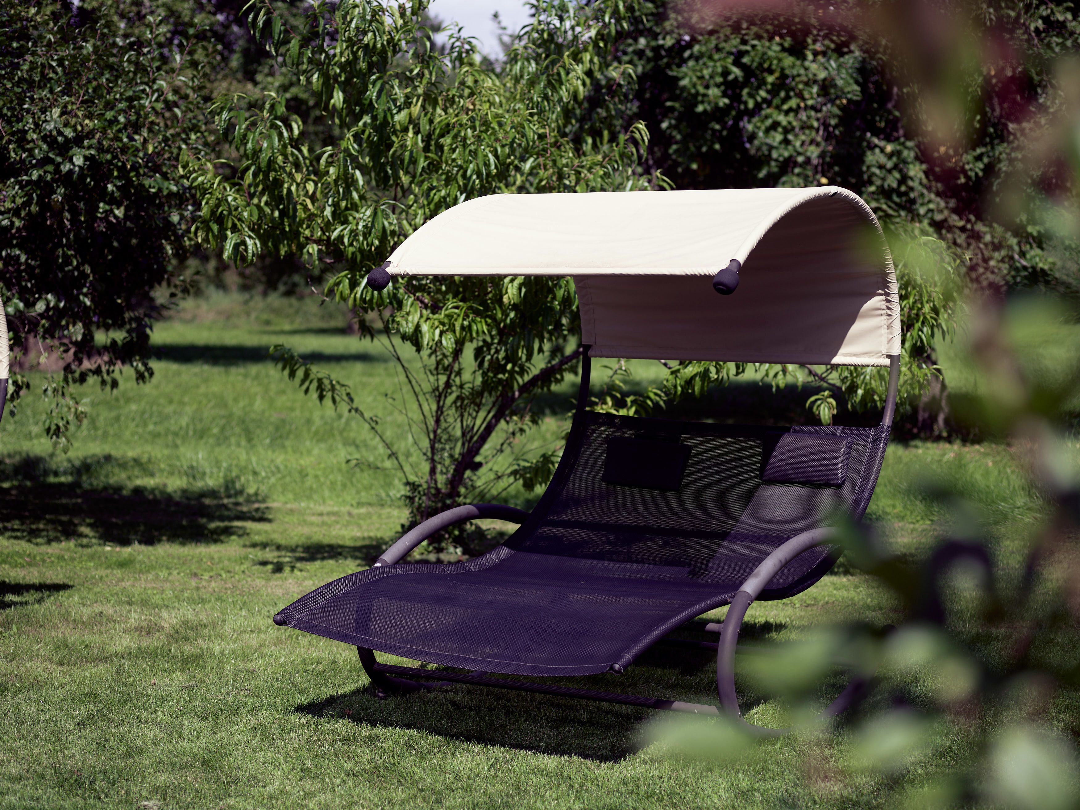 Una silla reclinable con dosel en un espacio al aire libre con césped.