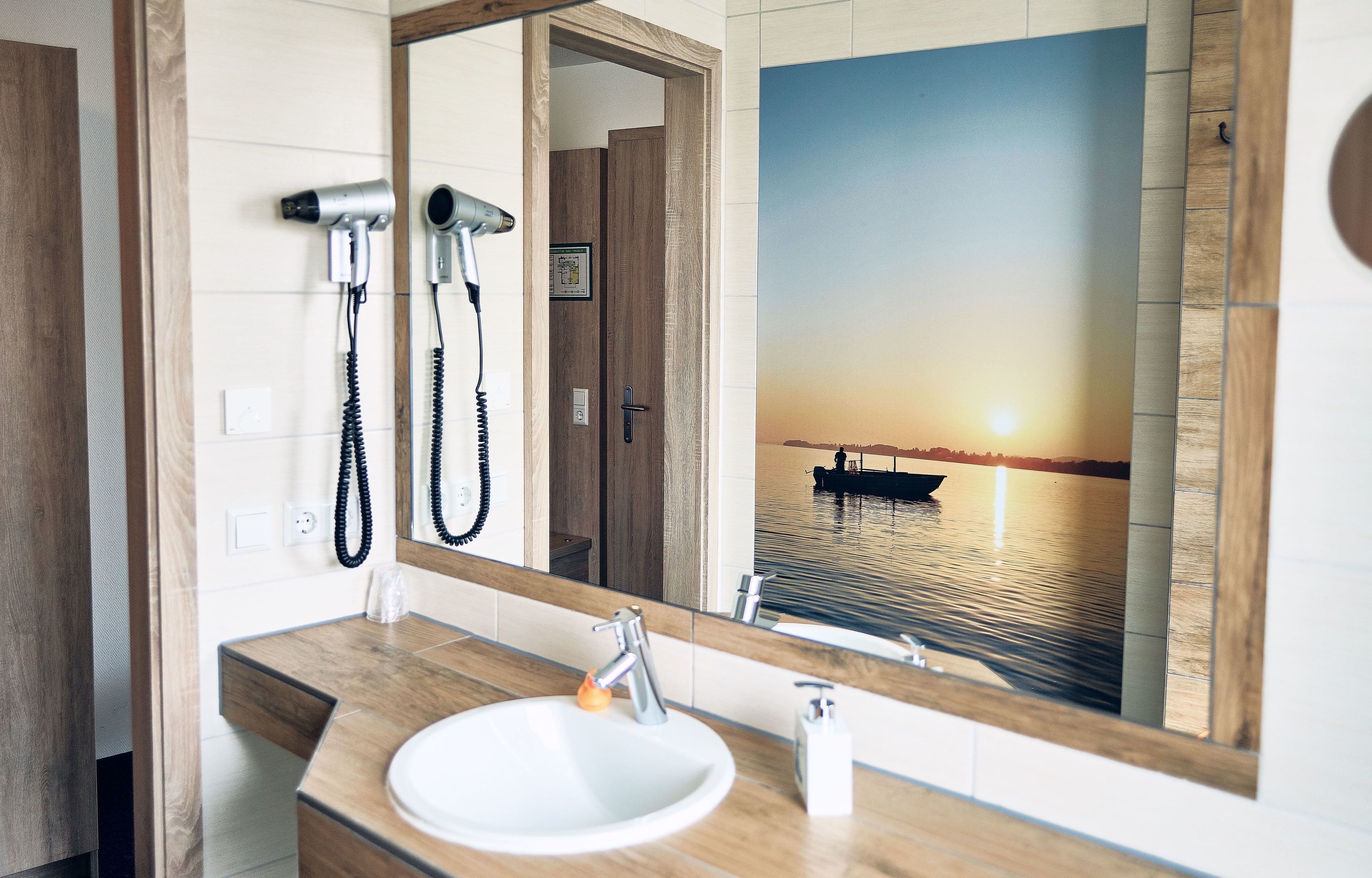 Une salle de bain avec un meuble-lavabo en bois, un évier, un miroir et un sèche-cheveux.
