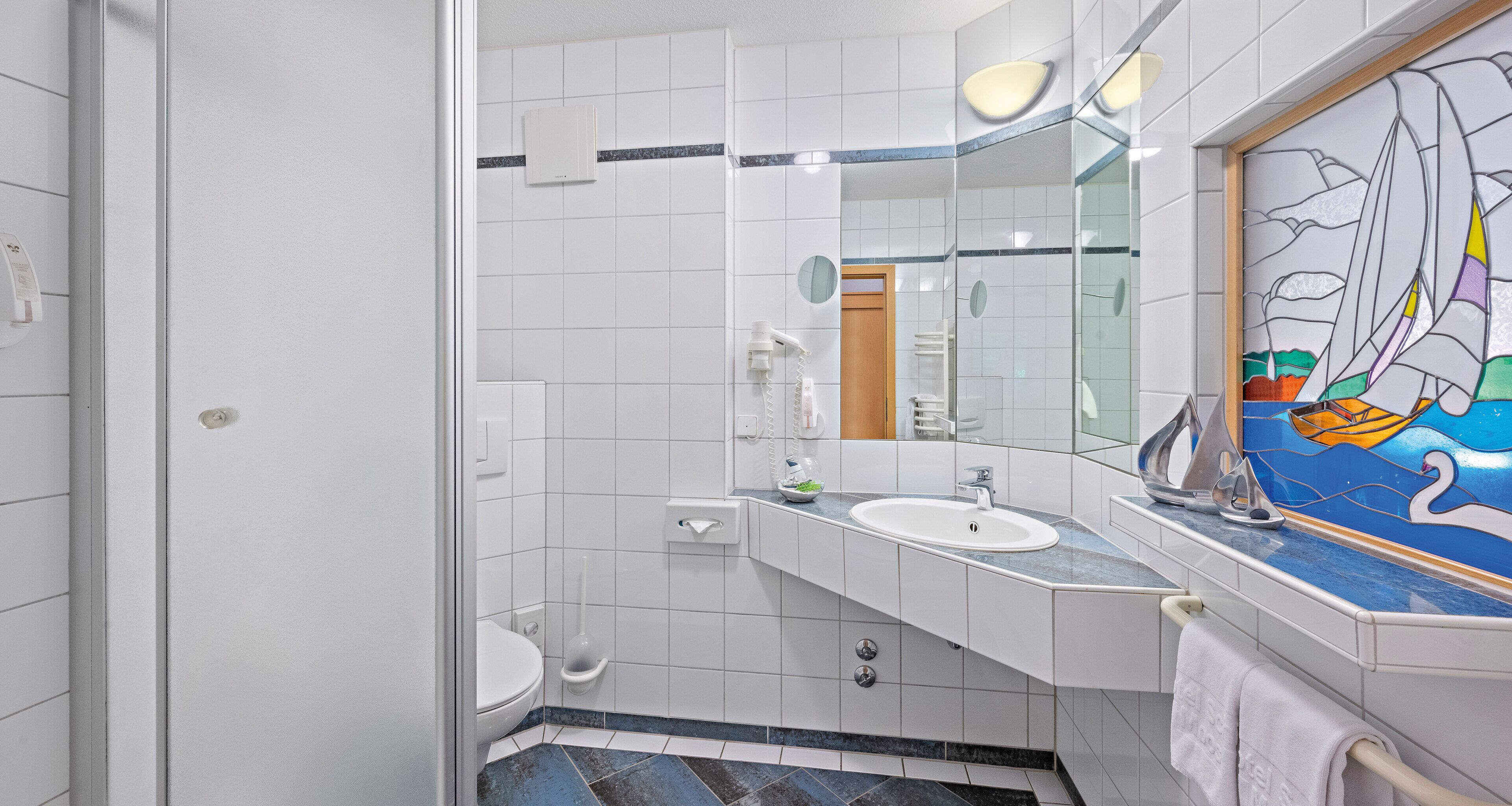 Un bagno con un lavandino bianco, uno specchio e una cabina doccia in vetro.